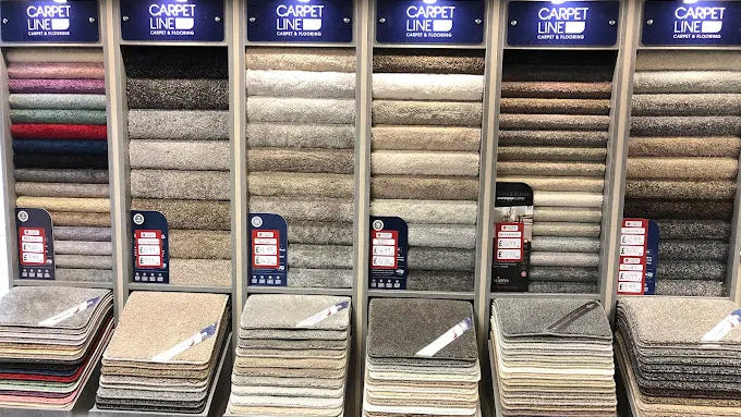 Display of carpet samples with 'Carpet Line' branding in a showroom.